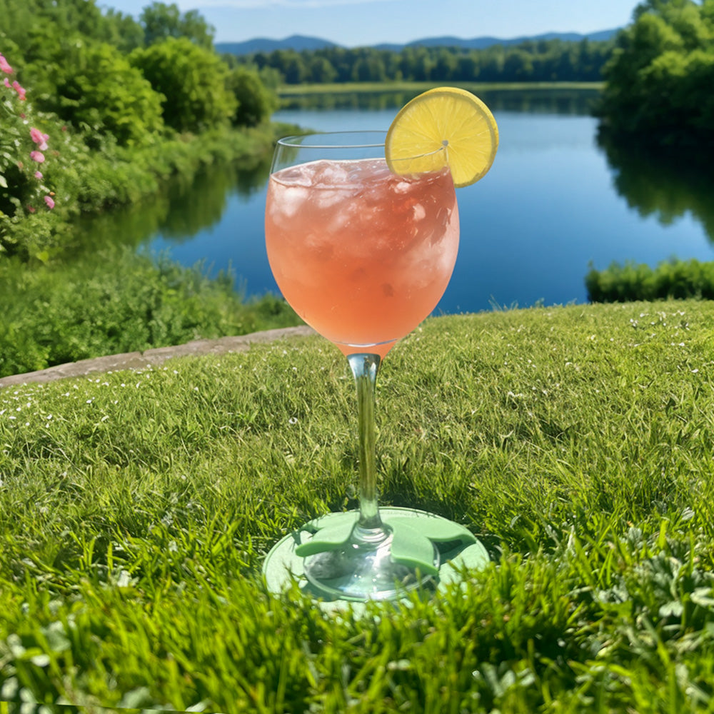 The Glass Slipper wine glass holder coaster securing a cocktail on grass during an outdoor picnic